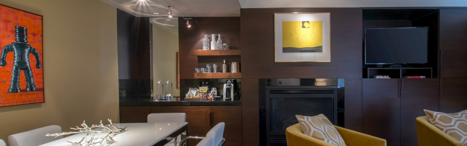 A modern living room with a white dining table, yellow chairs, wall art, a fireplace, and a TV mounted above. The sentence ends.