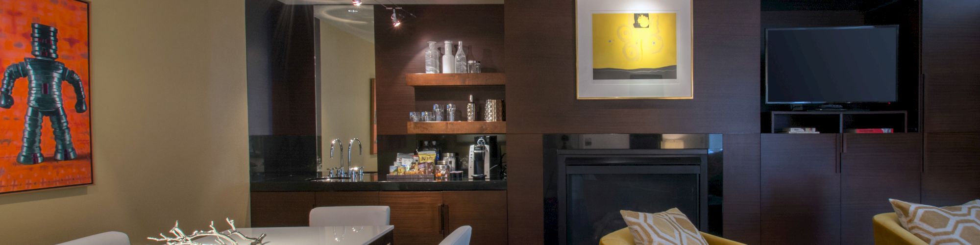 A modern living room with a white dining table, yellow chairs, wall art, a fireplace, and a TV mounted above. The sentence ends.