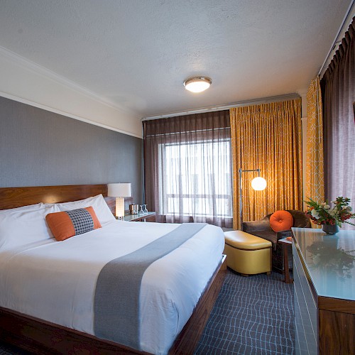 Superior King Room - A modern hotel room with a large bed, stylish decor, a flat-screen TV, a seating area, and floor-to-ceiling curtains by the window.