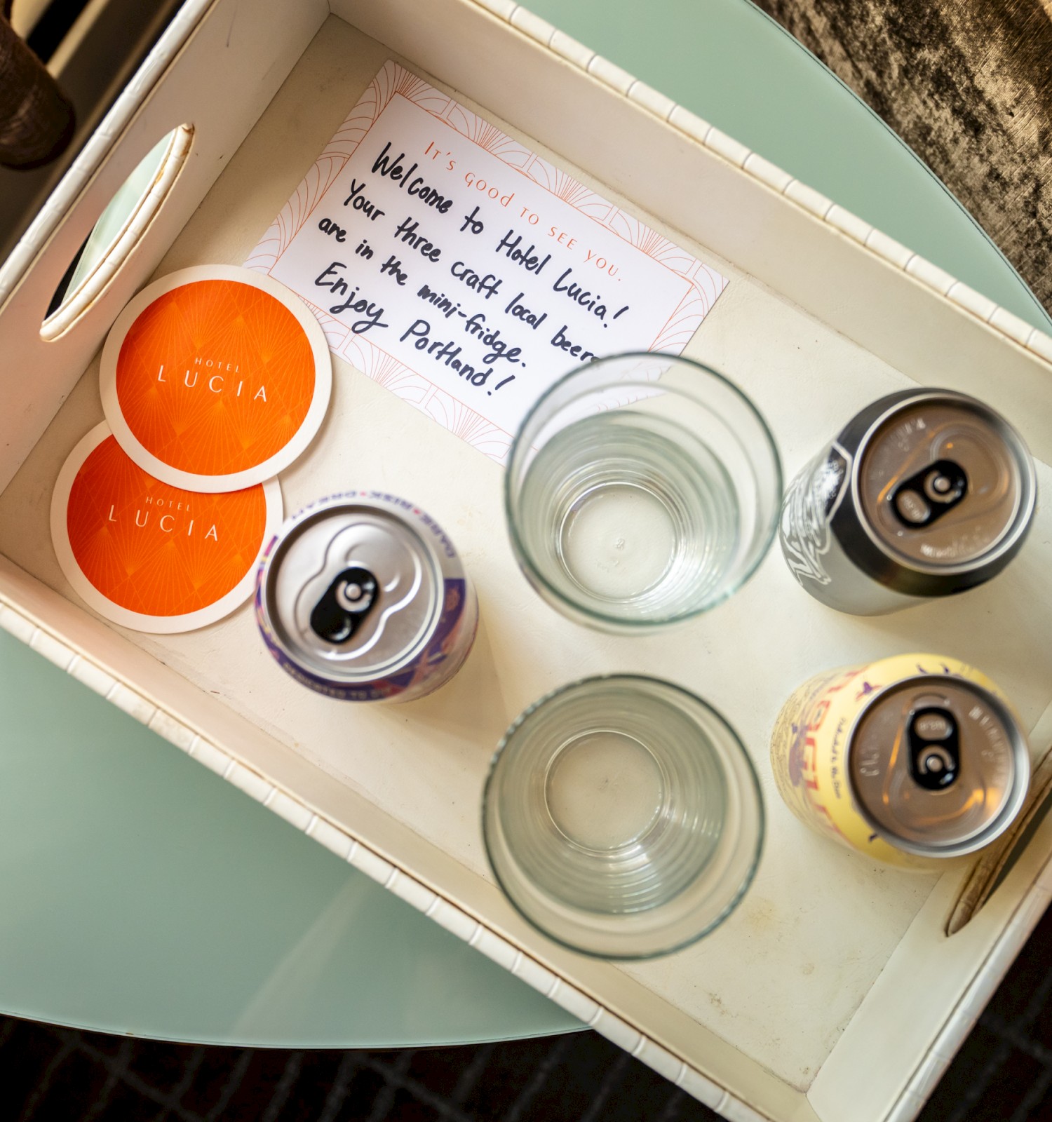 A tray with two glasses, three cans, two coasters labeled 