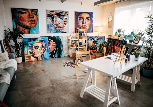 An art studio with vibrant portraits on the walls, a table with painting supplies, and a cozy seating area by the window.