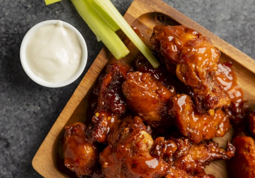 Sticky barbecue chicken wings on a wooden board with celery sticks and a dip, glossy sauce, savory and saucy finish.